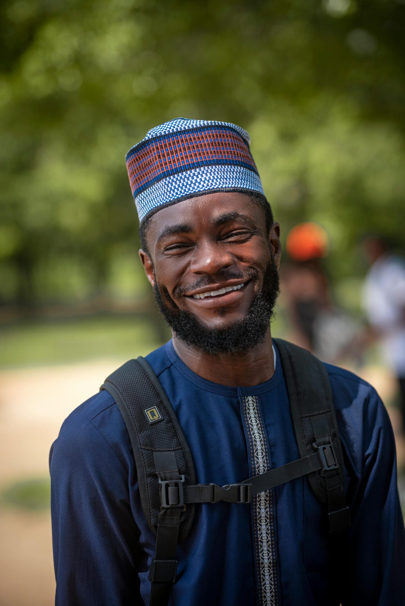 A cheerful Nigerian man wearing traditional attire smiles outdoors in Abuja.
